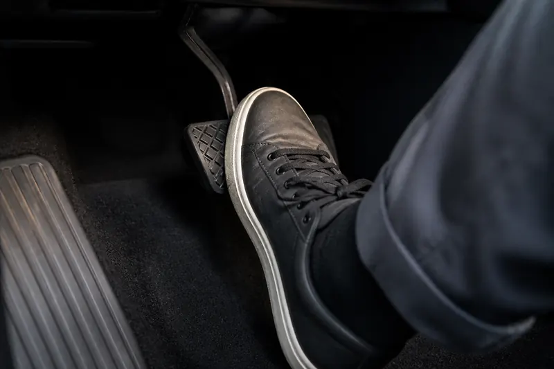 A driver's foot easing onto the brake pedal