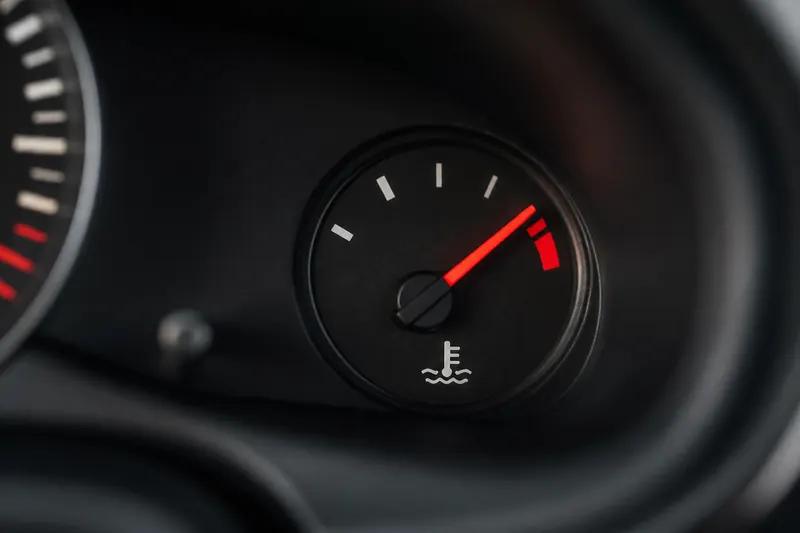 A dashboard temperature gauge with the needle in the red