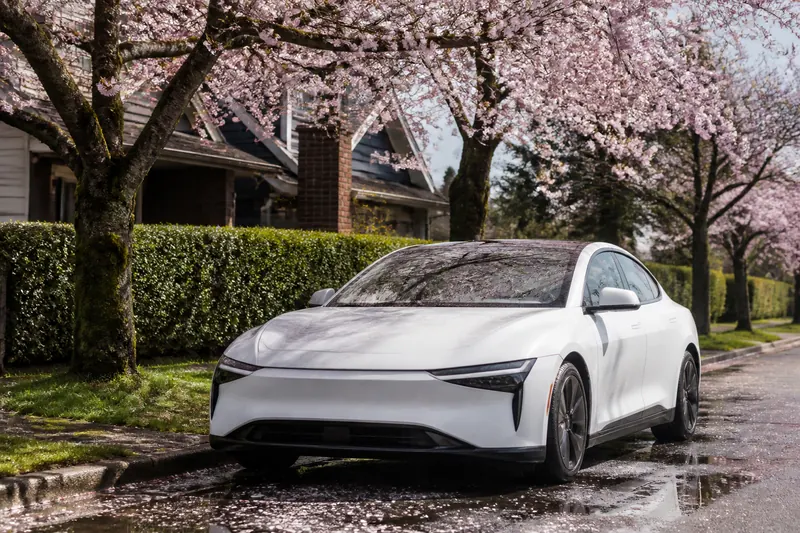 A car parked under blooming cherry trees on a quiet street on a sunny spring day