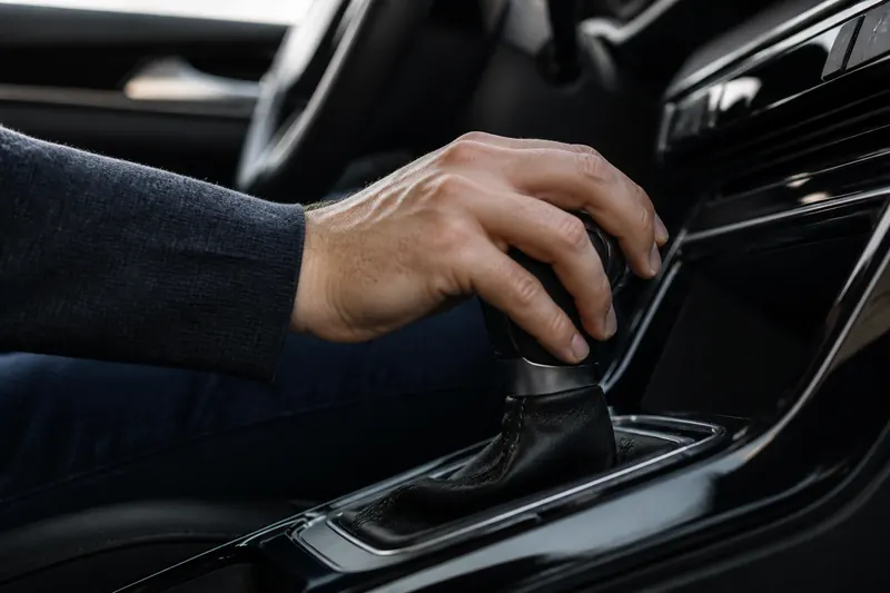 A hand on the gear shifter of a car