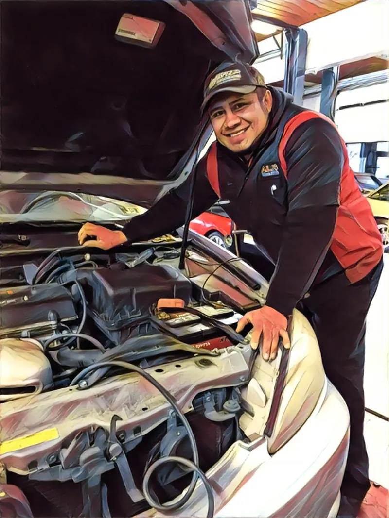 Luis smiling over the engine of a car he is working on
